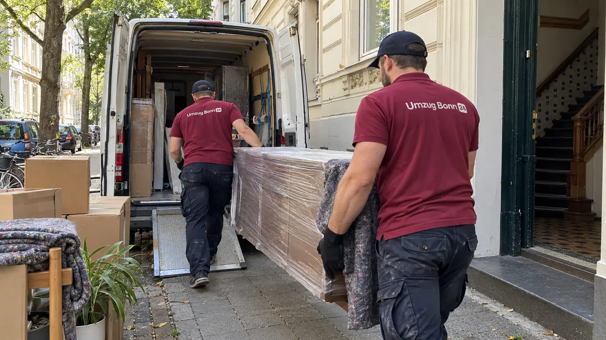 Umzug Bonn: zwei Umzugshelfer von Umzug Bonn 24 tragen einen verpackten Schrank aus einem Altbau zum Transporter