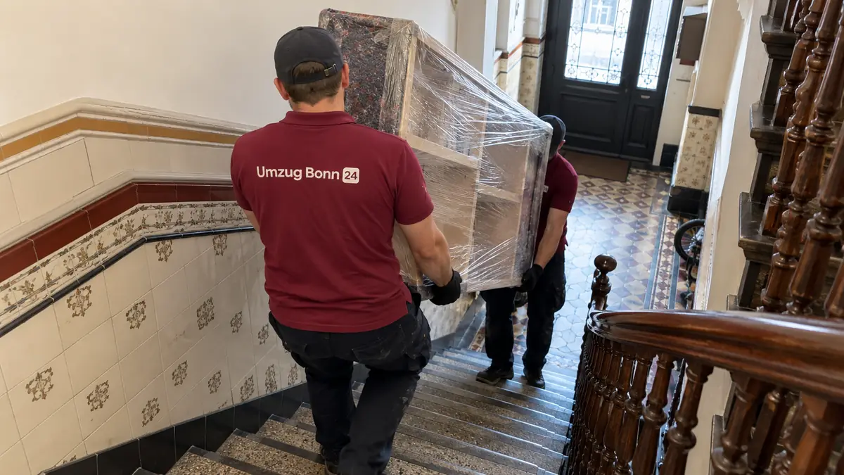 Altbau-Umzug Bonn: Umzugshelfer tragen ein Regal durch ein gefliestes Treppenhaus